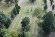 Aerial view of a cemetery featuring numerous graves arranged in neat rows amidst green grass.