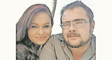 A man and woman smiling together, posing for a photo in a casual setting.