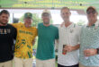 Five men smile and pose together at a lively beer tent, surrounded by festive decorations and drinks.