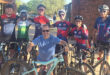 Several people of various ages and backgrounds stand together with their bikes, showcasing a sense of community and enjoyment.