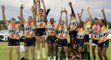 A group of men in yellow and black shirts proudly displaying their trophies in celebration.