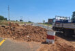 A truck standing along a road where a pipe is being repaired.