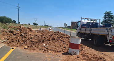 A truck standing along a road where a pipe is being repaired.