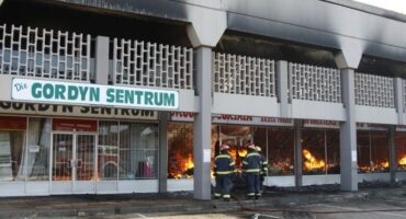 Firefighters battling a blaze at a store in the Eastdene center, with smoke and flames visible in the background.