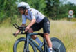 A cyclist navigating a dirt path, with a natural landscape in the background.