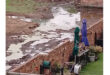 A backyard featuring a wooden fence surrounding a huge amount of sewage on the other side.
