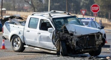White bakkie with front-end damage after collision at Acasia stop outside Ermelo, with police vehicle in background