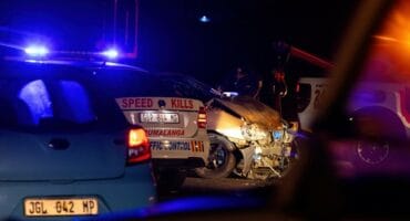 Close-up of a car's heavily damaged front end at night.