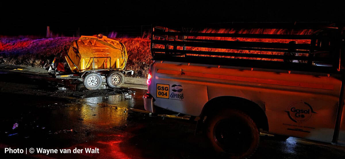 yellow diesel trailer, detached from a vehicle and partially off the road, is illuminated at night.