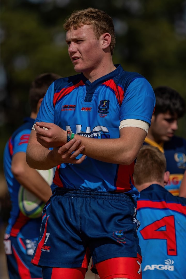 Jurgens Bezuidenhout, staan op die veld in 'n blou en rooi Ligbron-trui, voor ’n skrum.
