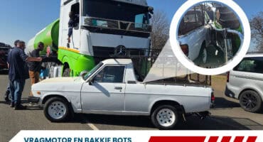’n Vragmotor en ’n wit Nissan 1400 bakkie staan naby mekaar op ’n pad na ’n ligte botsing in Ermelo. Polisie en omstanders is by die toneel.
