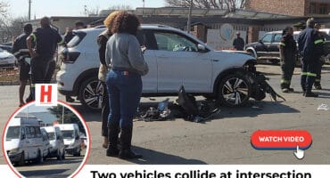 A white car with a heavily damaged front end is at the center of an intersection, surrounded by emergency personnel and bystanders. A smaller circular image in the bottom left shows two white minibus taxis parked on a street. Text at the bottom reads, "Two vehicles collide at intersection" with a "WATCH VIDEO" button next to it.
