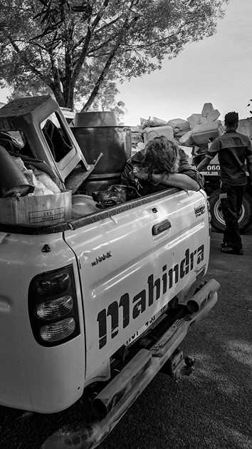 ’n Man sit agter op ’n bakkie met sy hond Lucy naby hom, sy kop in sy arm, kort nadat Ermelo-inwoners gehelp het om hulle van die straat af te kry.