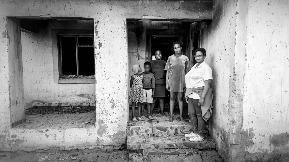 Two sisters and two children stand outside their burned house on Mthambama Street in Wesselton.