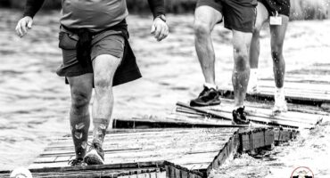 Three trail runners cross a wobbly wooden bridge over water during the Glen Aggy Trail Run in Amsterdam, Mpumalanga.