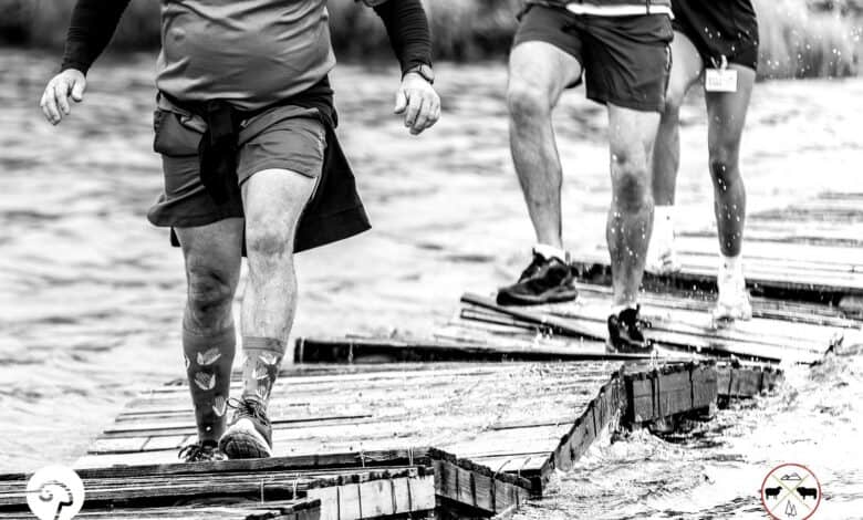 Three trail runners cross a wobbly wooden bridge over water during the Glen Aggy Trail Run in Amsterdam, Mpumalanga.