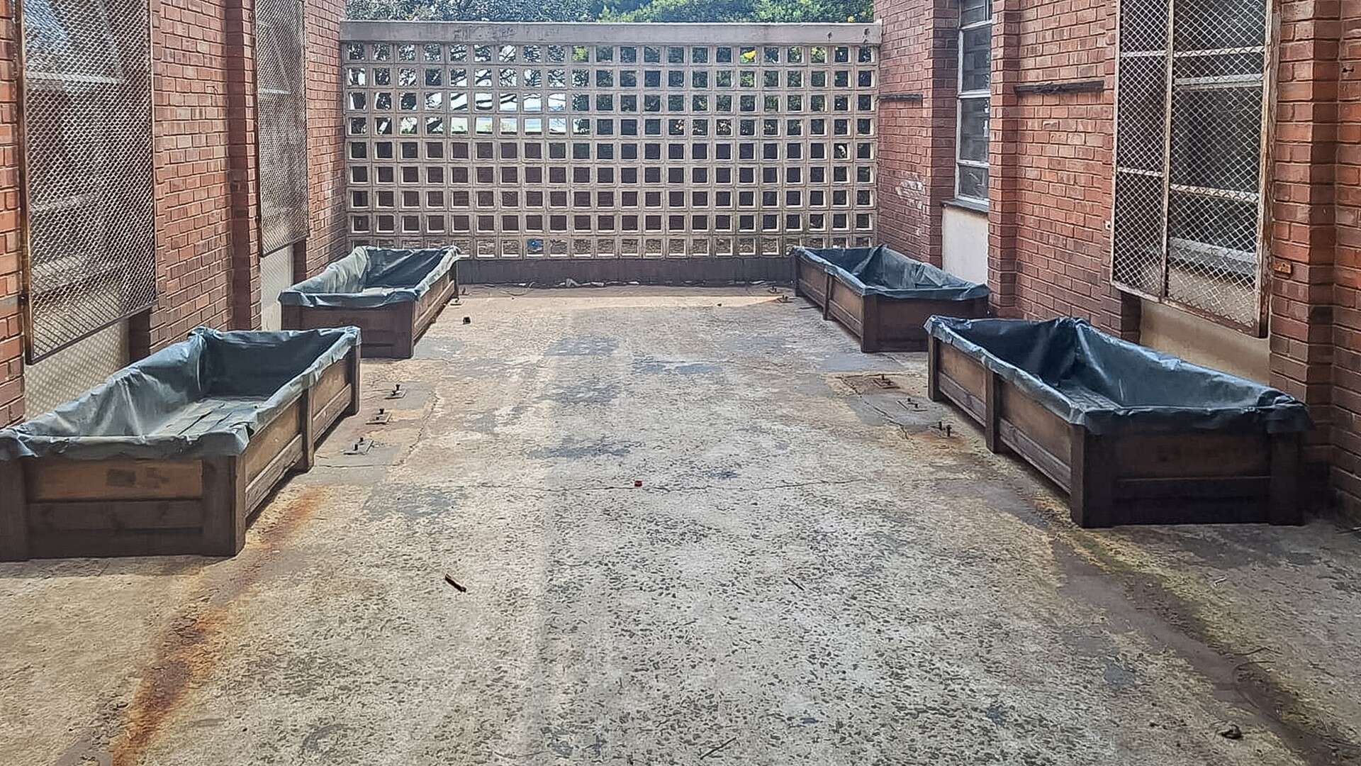 Alt text:Four large treated planting crates donated by the Ermelo Toyota Aspirant Knights to Children of the Dawn for their new vegetable garden.