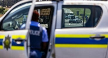 View of the N11 accident scene near Ermelo taken through a police vehicle window, showing the wreckage, police van and officer on scene