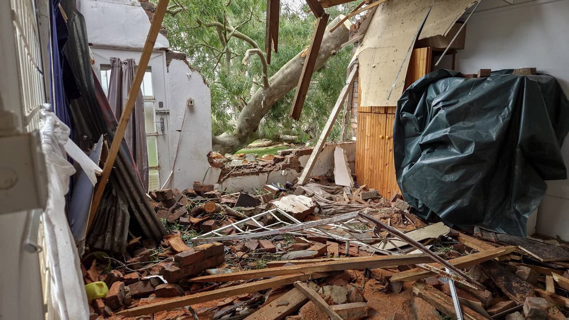 Hoofslaapkamer van die Van den Heevers ná die massiewe boom op die dak geval het, met gebroke dakbalke en verspreide hout en glas.
