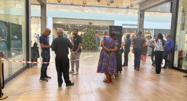 ACSU owner Oubaas de Jager and security officers stand near Ermelo Jewellers inside Merino Mall after an armed robbery, with mall goers nearby.