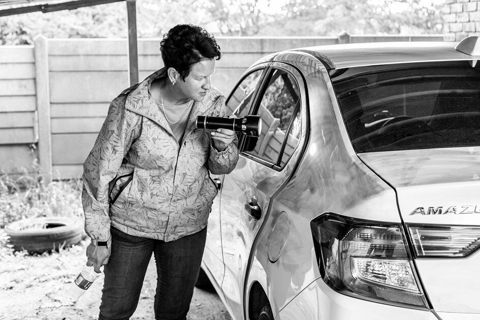 Detective Thelmari Aucamp inspects the recovered Honda sedan with a torch during the investigation into the Ermelo Jewellers armed robbery.