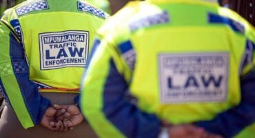 Agterkant van twee verkeersbeamptes in Mpumalanga met klere waarop “Mpumalanga Traffic Law Enforcement” geskryf staan.