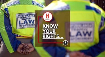 Back view of traffic officers’ uniforms at a roadblock in Ermelo, highlighting a mother’s claim she was told to pay fines before taking her sick toddler to hospital.