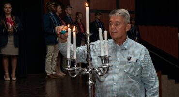 Mnr Gerhard Brand steek die kandelaar aan terwyl leiers en gr. 8s hul kerse voorberei