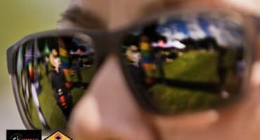 Woman wearing reflective sunglasses with the marathon finish line visible in the lenses at the TWK Assegaai 3-in-1 Marathon in Mkhondo.