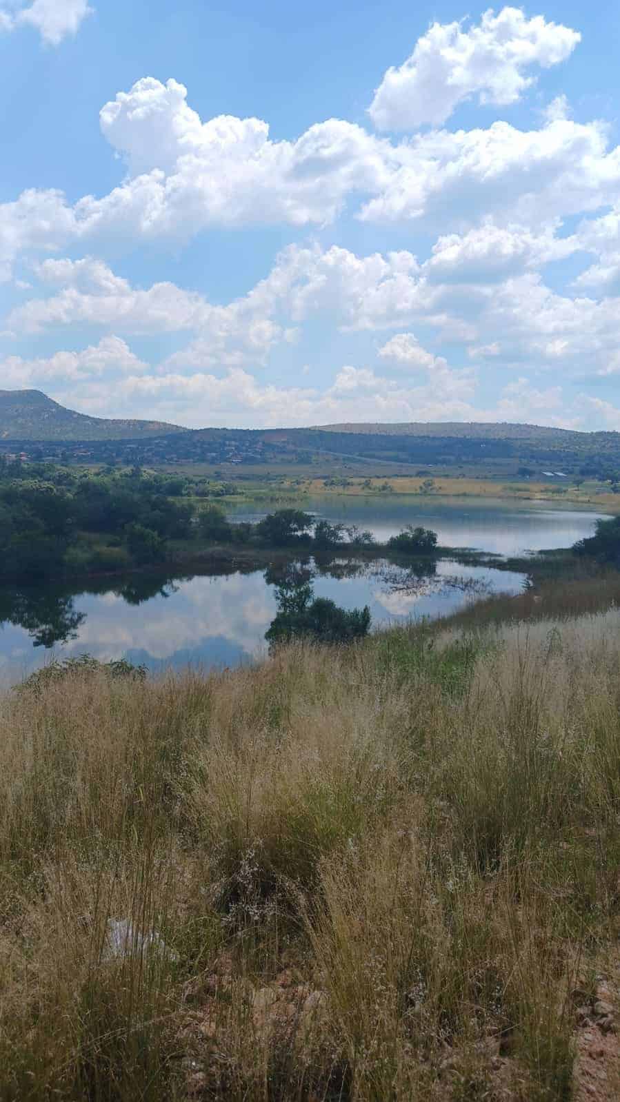 Polisielede staan by ’n dam in Phokeng waar konstabel Gift Mota gesterf het tydens die uitvoering van sy pligte.