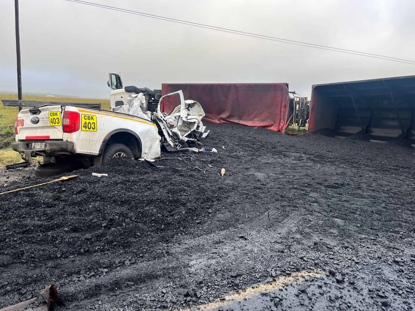 Overturned truck and heavily damaged bakkie partially buried in spilled coal after fatal crash near Ermelo on Piet Retief Road.