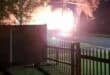 Helder flits en ligglans naby straat agter ’n heining in die nag