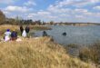 Police divers recovering the body of a woman from Douglas Dam while SAPS and Spartan Security stand on the shoreline