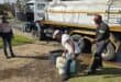 Inwoners vorm rye langs Generaal Bothastraat terwyl water uit ’n konstruksievoertuig uitgedeel word te midde van voortdurende wateronderbrekings in Ermelo.