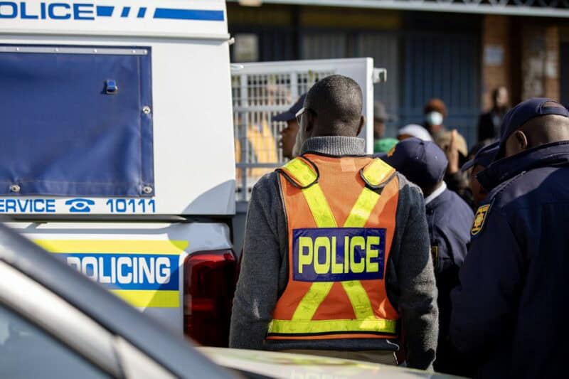 Community members standing near a police van where a man was escorted into custody in Ermelo.