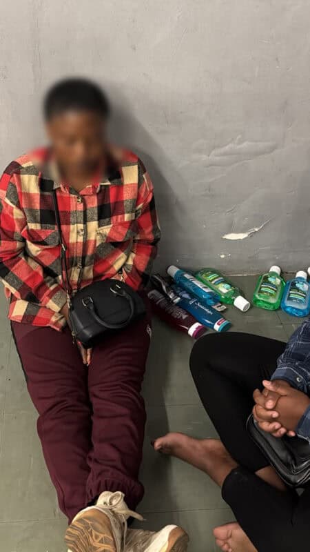 Two women seated on the floor next to several personal care products following an alleged shoplifting incident at PEP Stores.