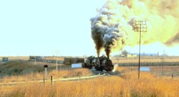 Two Class 24 steam locomotives depart Breyten with the 06:00 freight service to Lothair on May 3, 1983.