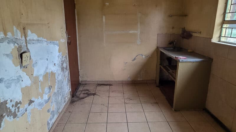 Empty kitchen with apparent water damage to the walls.