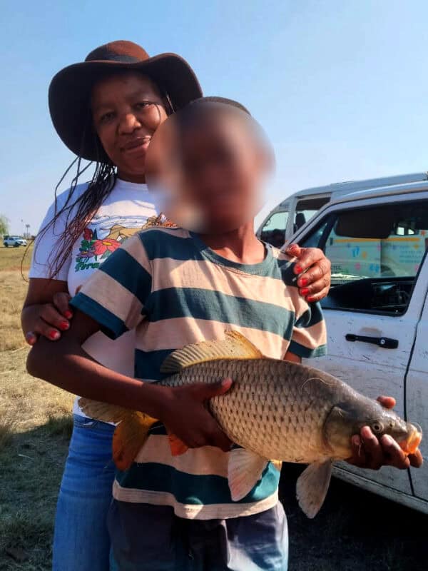 CMR CYCC child proudly holds a large carp caught during the fishing competition.