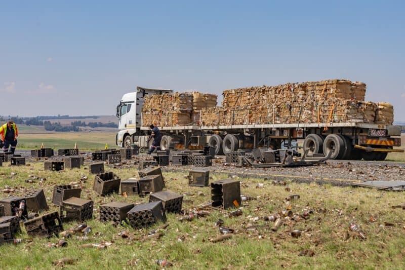 A truck passes on the shoulder as beer bottles, broken glass and crates lie scattered across the Ermelo-Morgenzon road.