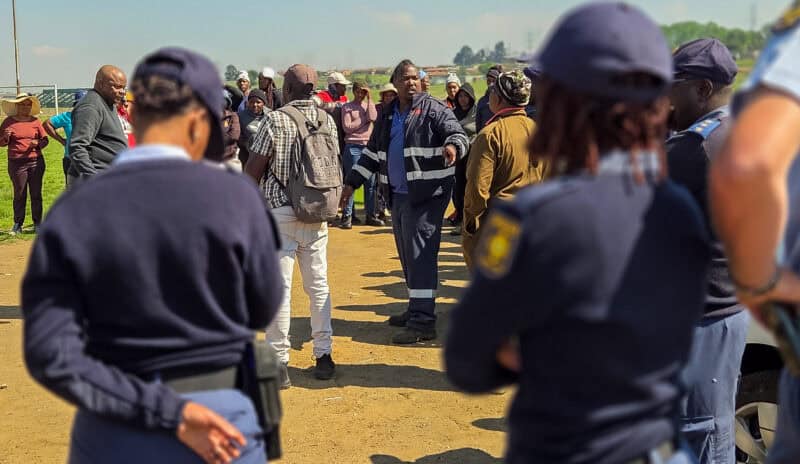 Police officers monitor a gathering near the Mpumalanga Stadium in Wesselton, Ermelo.
