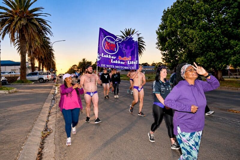 Ermelo runners carry a purple Hollard Daredevil Run banner promoting men’s health awareness.