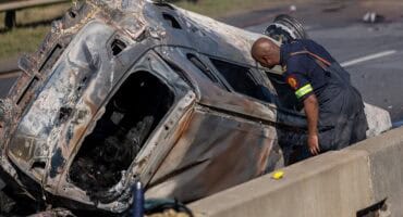 ’n Brandweerman van Msukaligwa se Brand- en Reddingsdienste ondersoek die uitgebrande wrak van ’n sedan ná ’n noodlottige botsing op die N2 buite Ermelo.