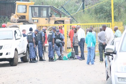 Police search squatters this morning as they leave Secunda dumping site.