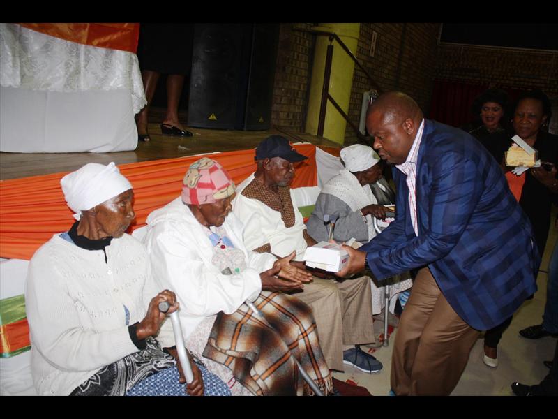 Mr Freddy Nkambule (MMC for Technical and Engineering Services) hands over gifts to the elderly.