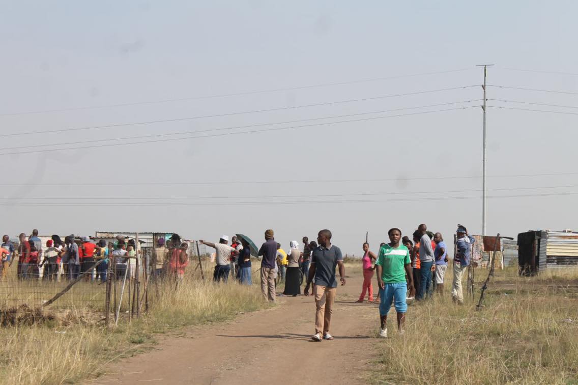 Residents standing outside the shack where stolen goods were found.