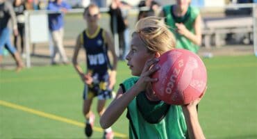 A young girl holding a ball in her hands.