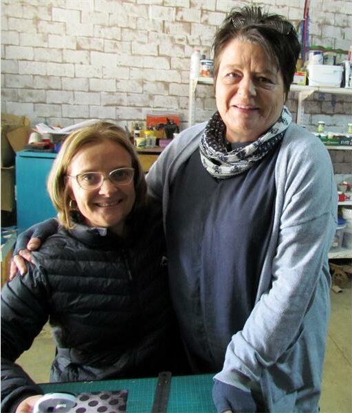 Two women standing next to each other in a workshop.