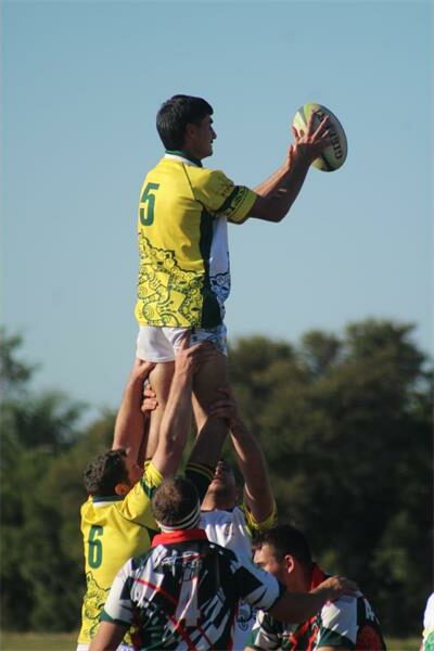 A rugby player is in the air with his arms up.