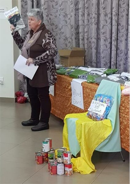 A woman standing next to a table with food and other items.